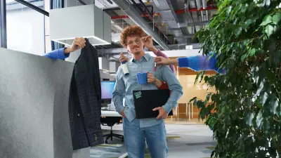 person being handed everything needed to work: computer, blazer, etc.