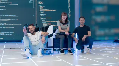 Três jovens, dois homens e uma mulher, posam em frente a um grande ecrã a exibir código, possivelmente uma startup tecnológica.