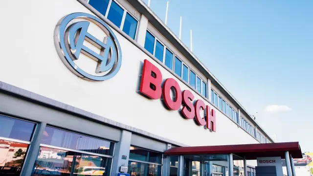 Foto exterior de um edifício Bosch moderno com um grande logotipo da Bosch contra um céu azul brilhante.